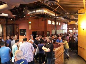 Crowd of people mingling inside in a bar.