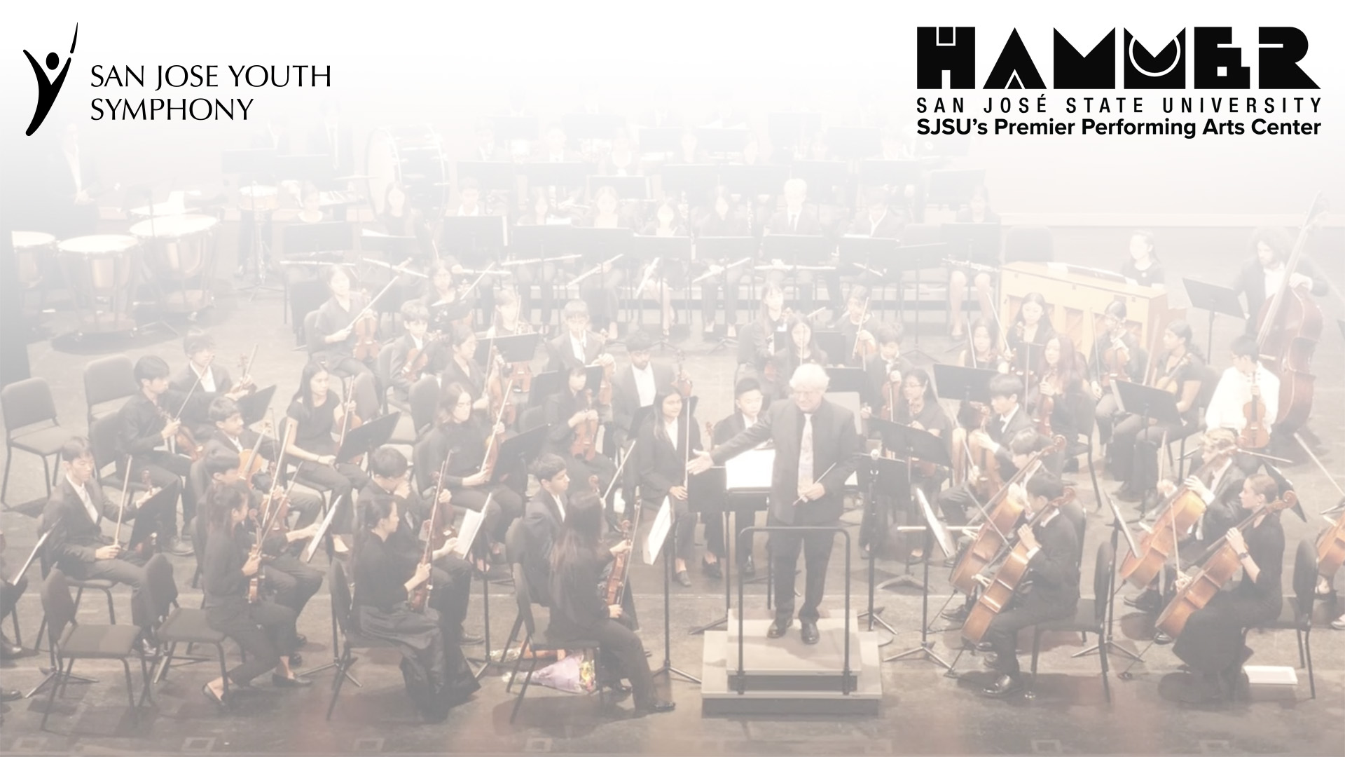 Screenshot Orchestra band seated around a conductor as he speaks