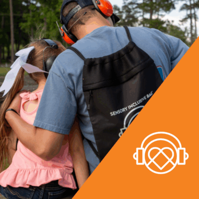 A man wearing protective headphones and a Kulture city Sensory Bag hugging a young girl beside him. In the right corner is the Kulture City logo