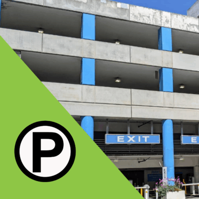 A grey and light blue parking structure and some exit signs for the lot. In the left corner is a parking pictogram